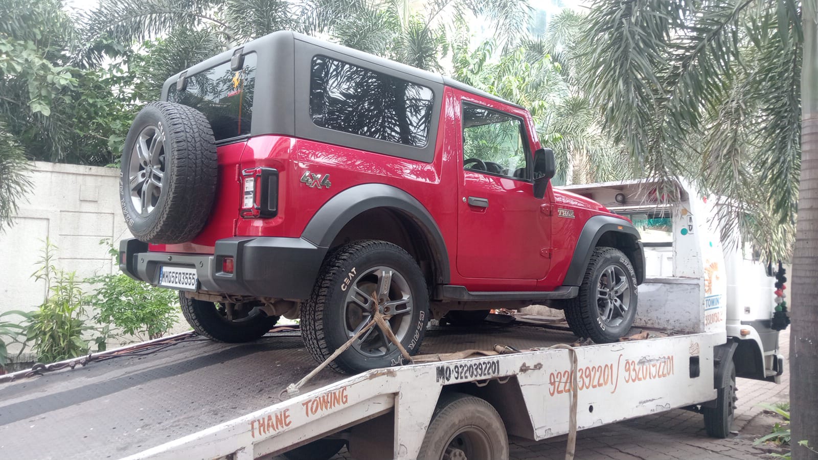 Red Mahindra Thar 4x4 being securely loaded onto a flatbed by Siddhivinayak Towing in a residential area.